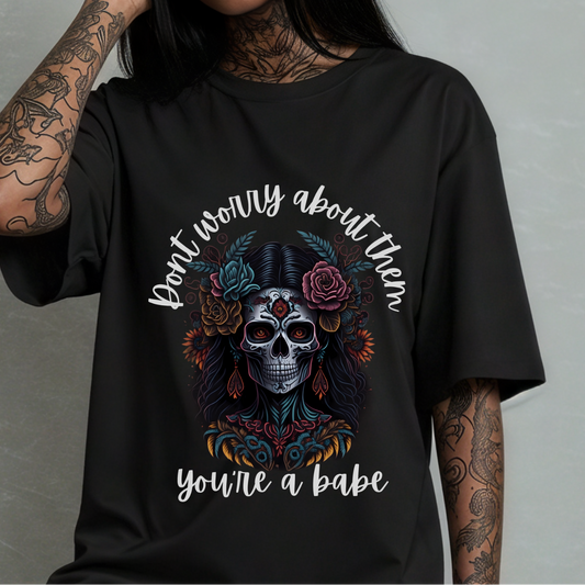 Person wearing a black t-shirt with a skull design and text against a gray background