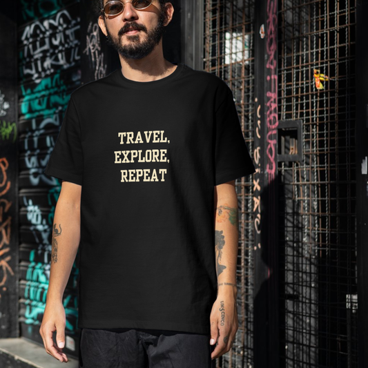 Man wearing a black t-shirt with 'TRAVEL. EXPLORE. REPEAT' text in front of a graffiti-covered wall.