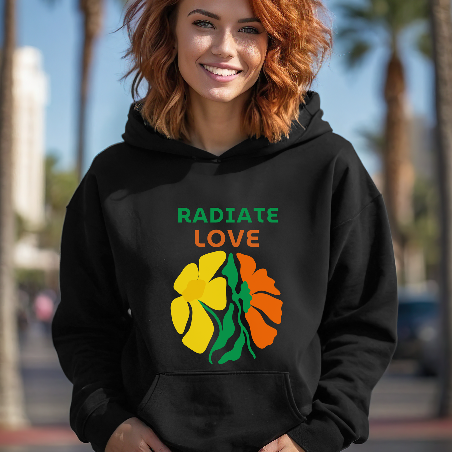 Person wearing a black hoodie with 'Radiate Love' and floral design outdoors.
