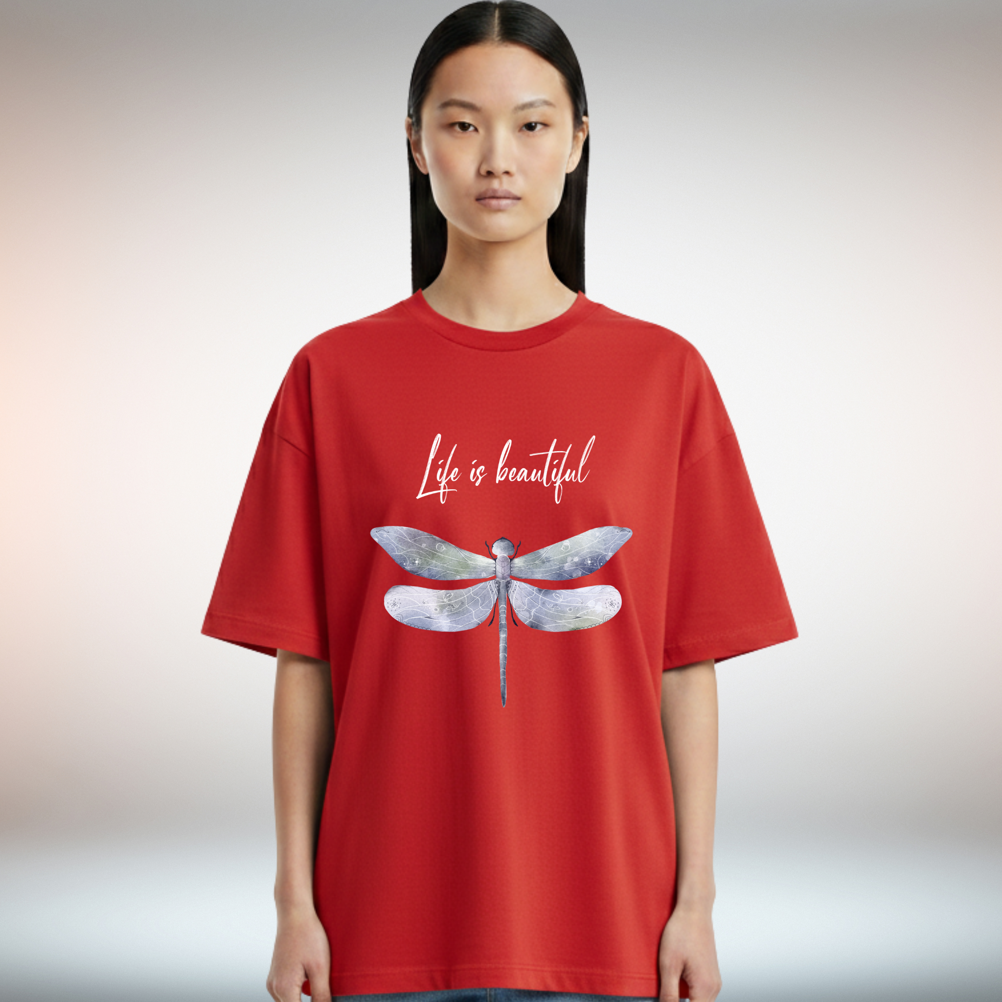 Person wearing a red t-shirt with a dragonfly and 'Life is beautiful' text on a plain background