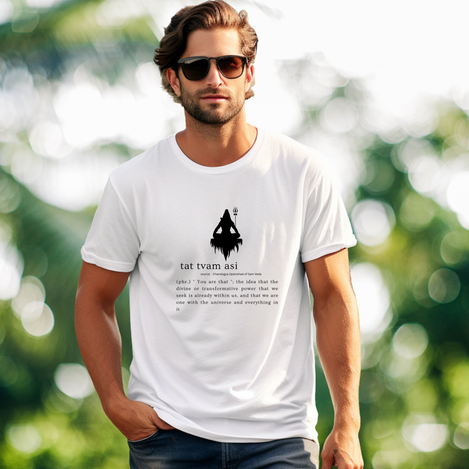 Man wearing a white t-shirt with a graphic design and text, standing outdoors with a blurred green background.
