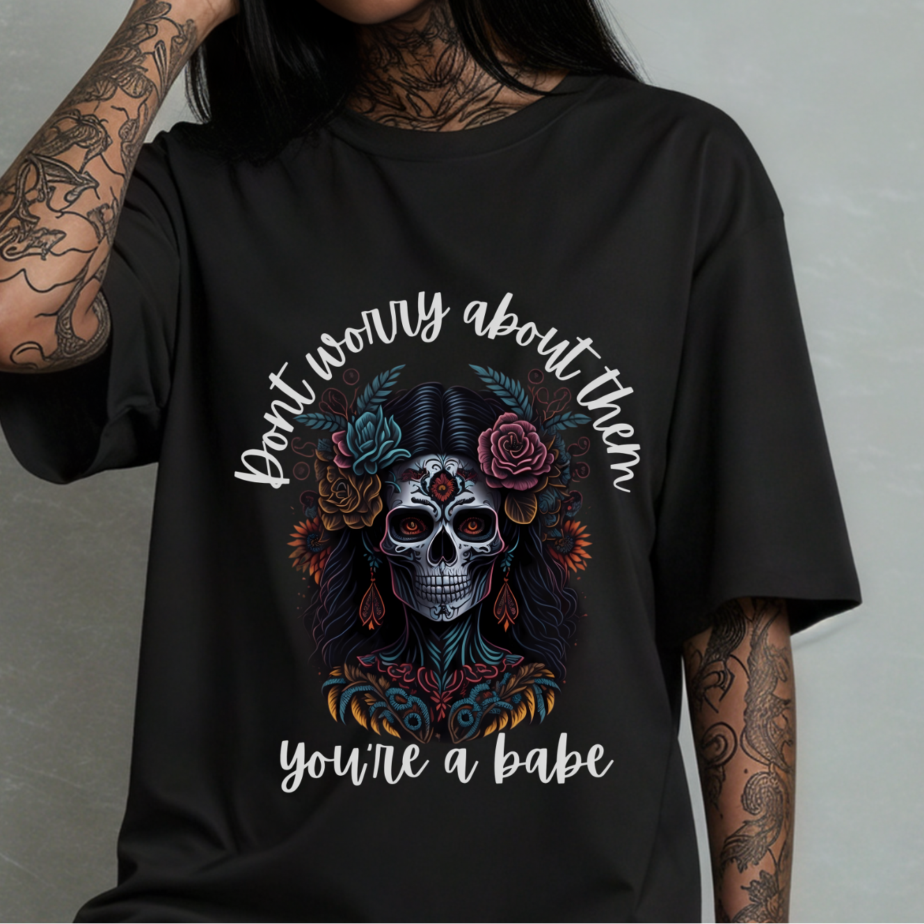 Person wearing a black t-shirt with a skull design and text against a gray background