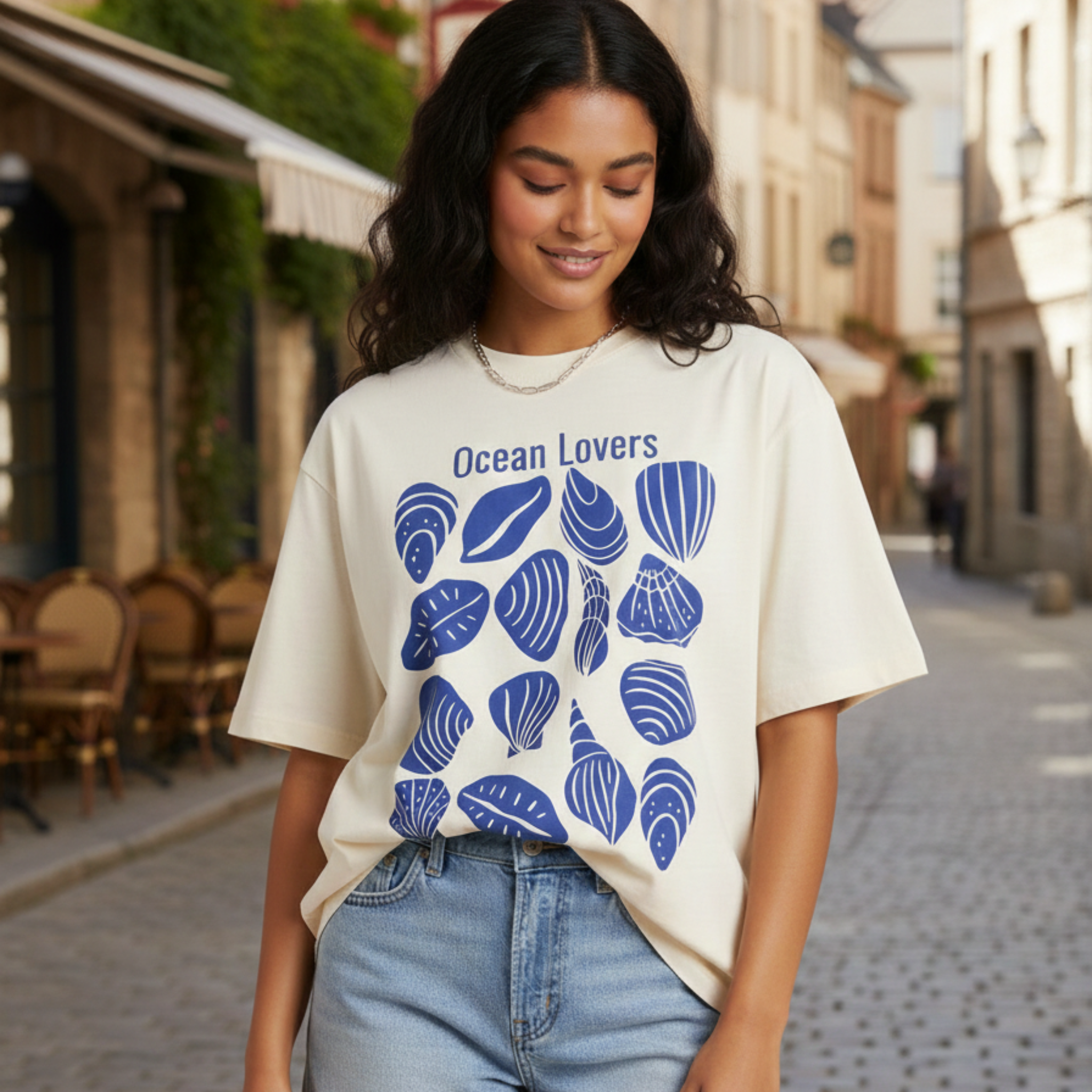Woman wearing a 'Ocean Lovers' t-shirt with blue shell designs on a street.