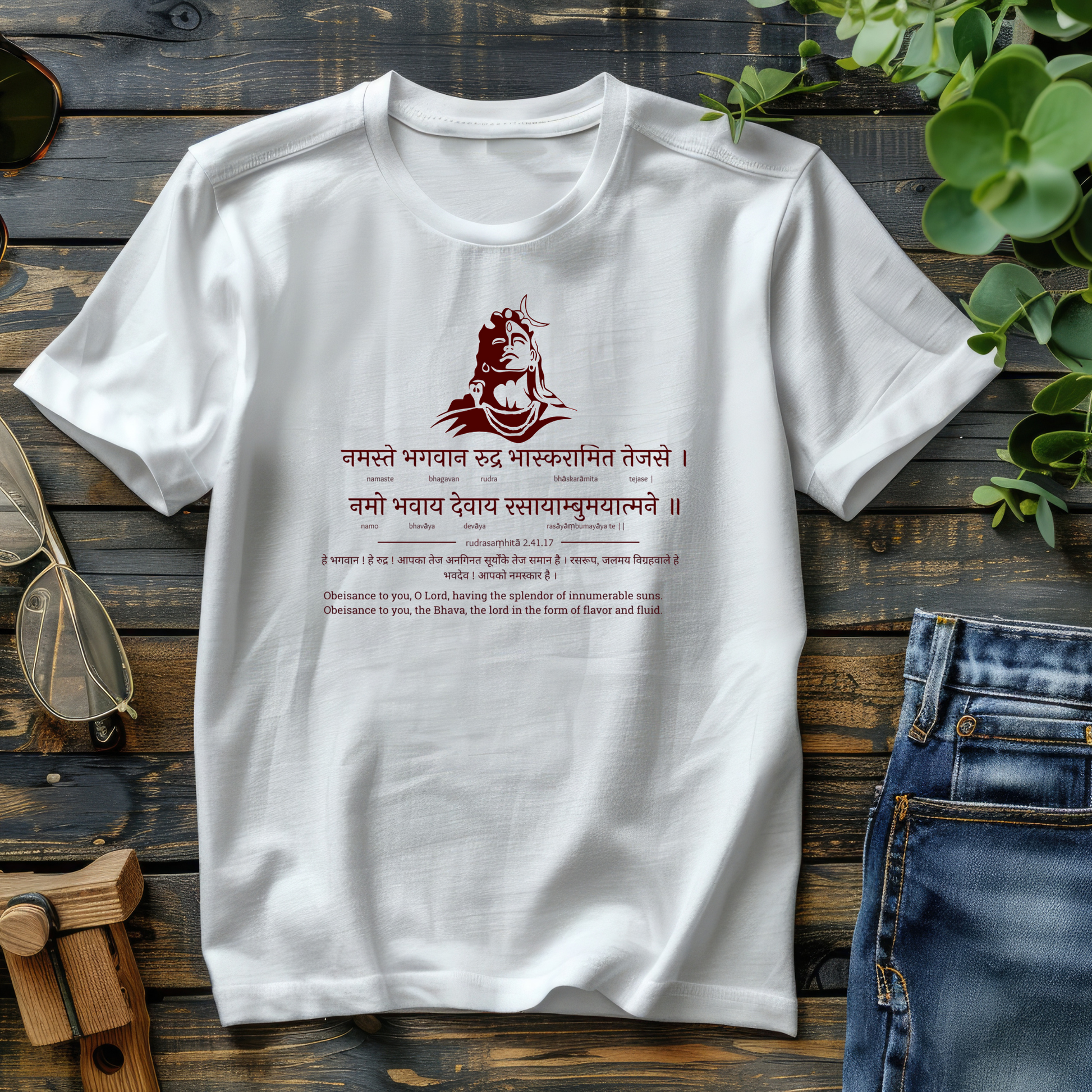 White t-shirt with red design and text on a wooden surface with jeans and sunglasses.