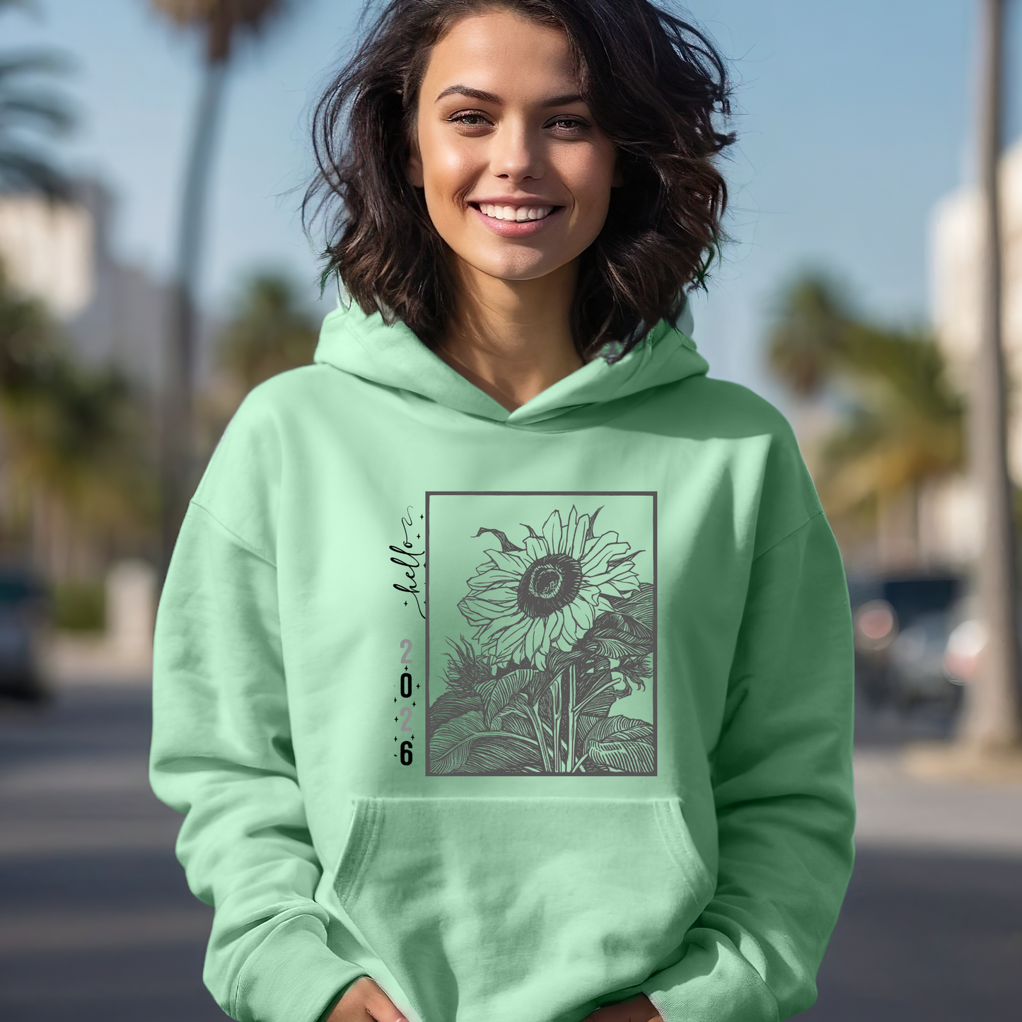 Person wearing a light green hoodie with a floral design on a blurred street background