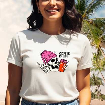 Person wearing a white t-shirt with a graphic design and text 'Coffee is Life' against a beach background.