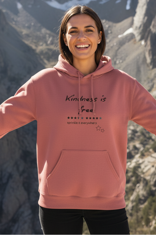 Person wearing a pink hoodie with text in front of mountainous landscape