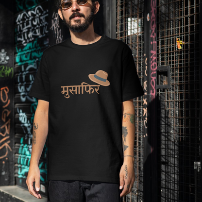 Person wearing a black t-shirt with a logo and text, standing against a graffiti-covered wall.