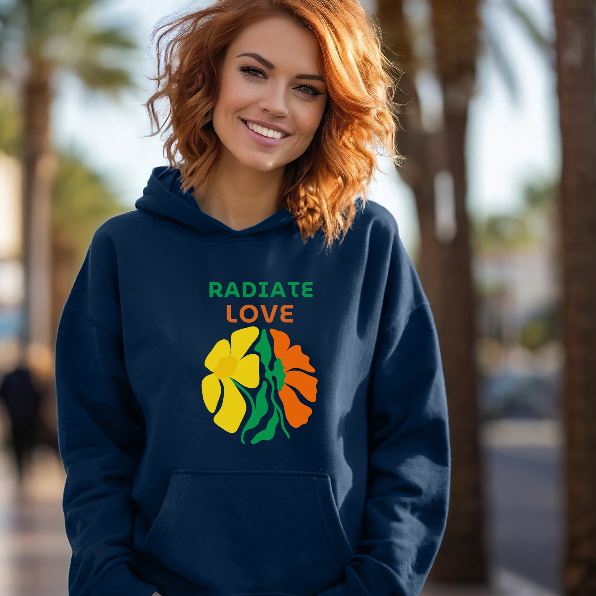 Woman wearing a navy hoodie with floral design and 'Radiate Love' text outdoors.