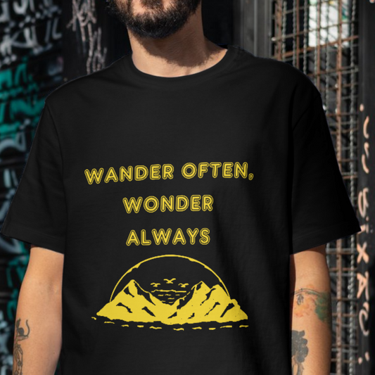 Person wearing a black t-shirt with yellow text and graphic, standing against a graffiti-covered wall.